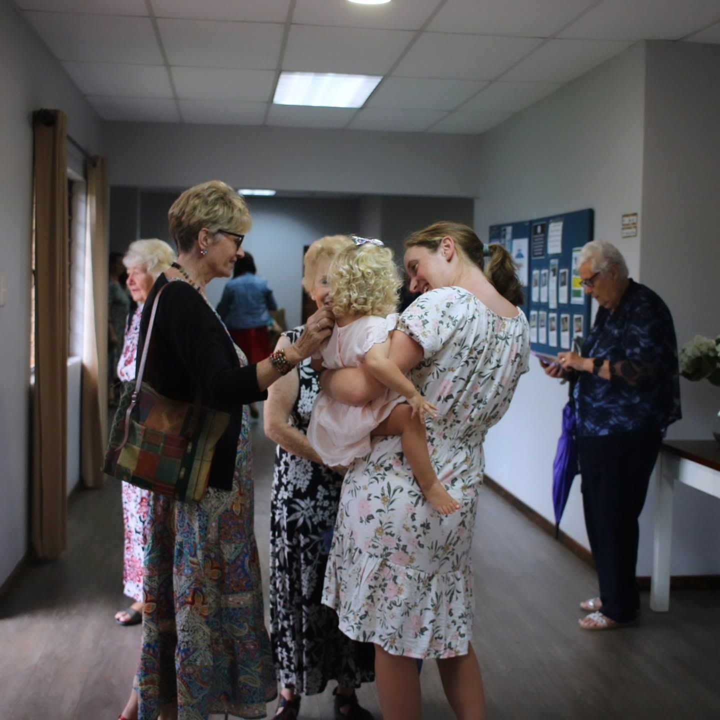 Ladies of the church greeting a young mother and her toddler in the foyer