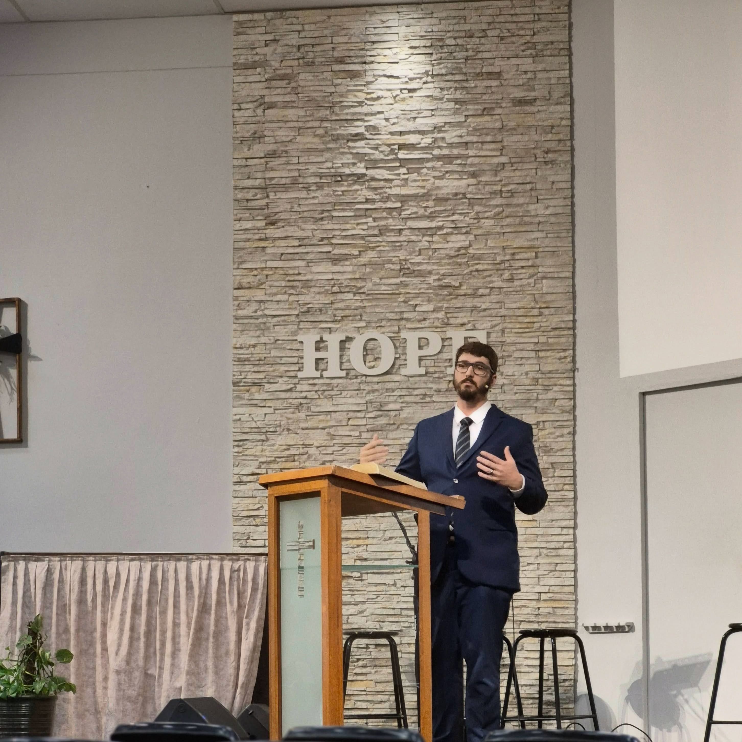 A preacher at the pulpit in front of the stone wall